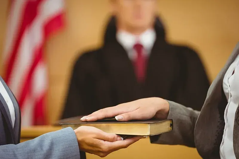 hands swearing before a book and a judge