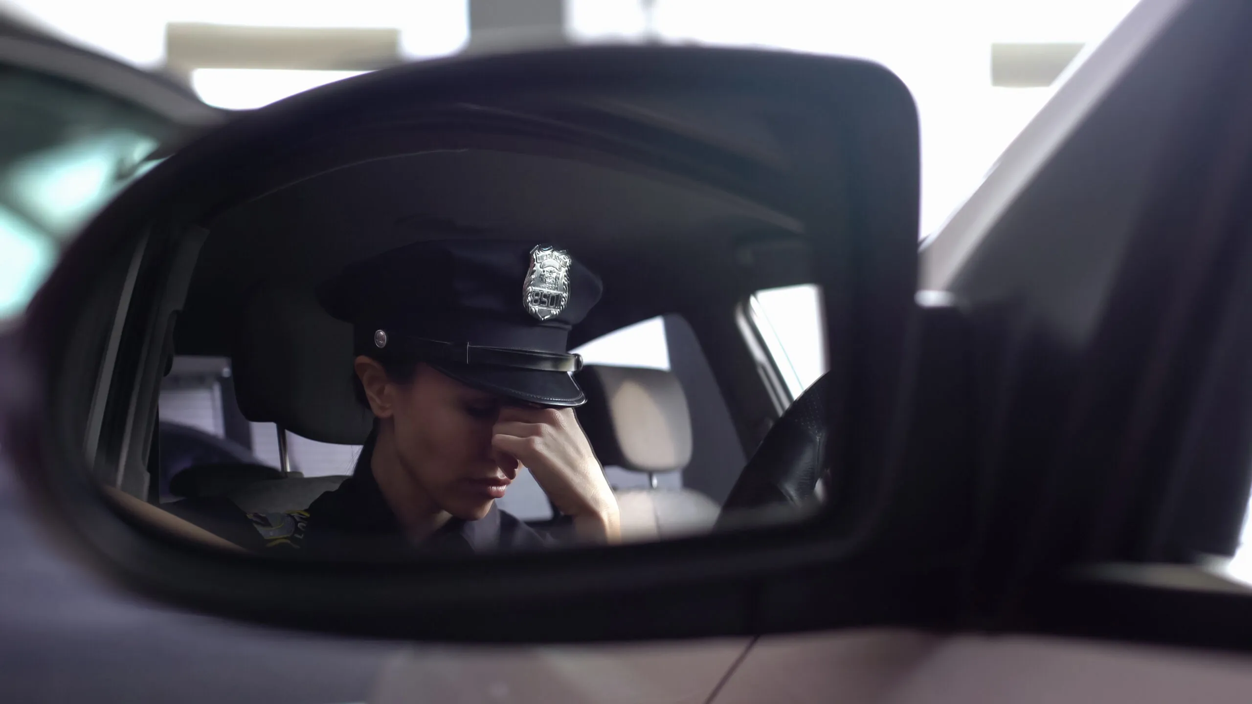 a police officer sitting in a car holding the bridge of their nose during stress, tiredness or depression.