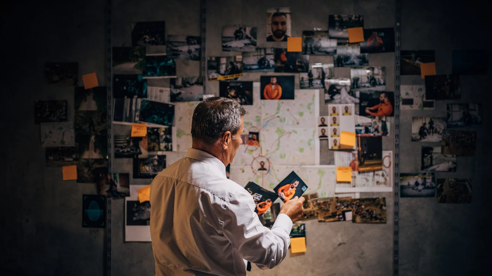 a man standing in front of a wall covered in pictures