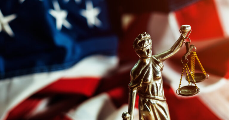 a statue of lady justice in front of an american flag