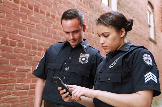 a man and a woman in police uniforms looking at a cell phone
