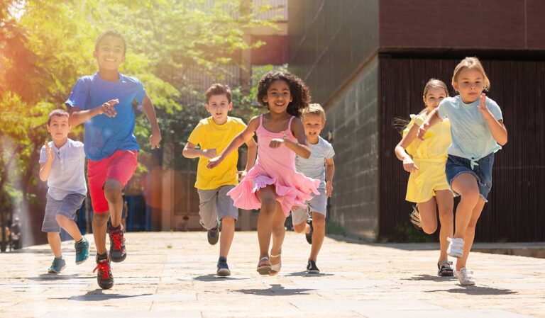 a group of children running down a sidewalk
