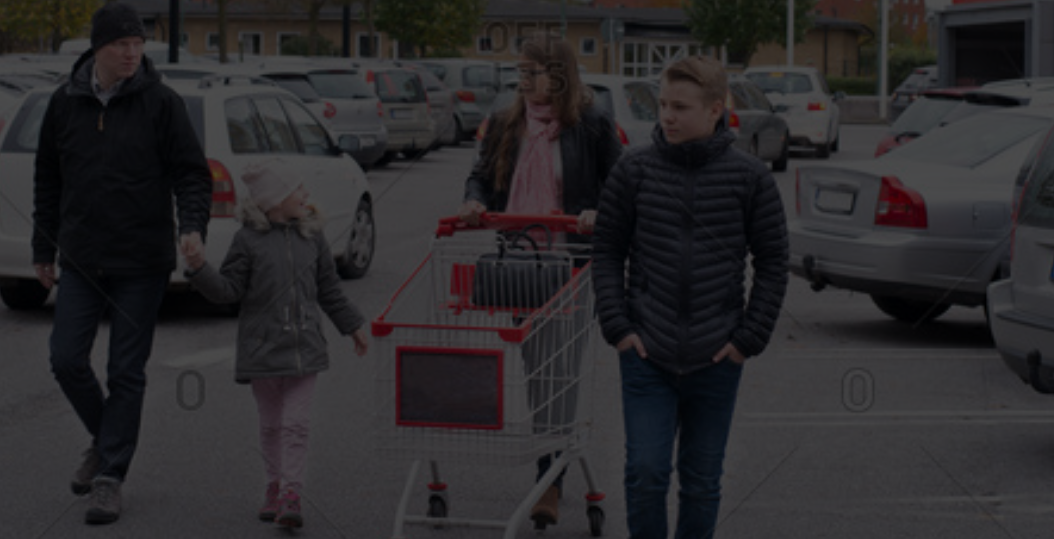 a group of people walking down a street with a shopping cart