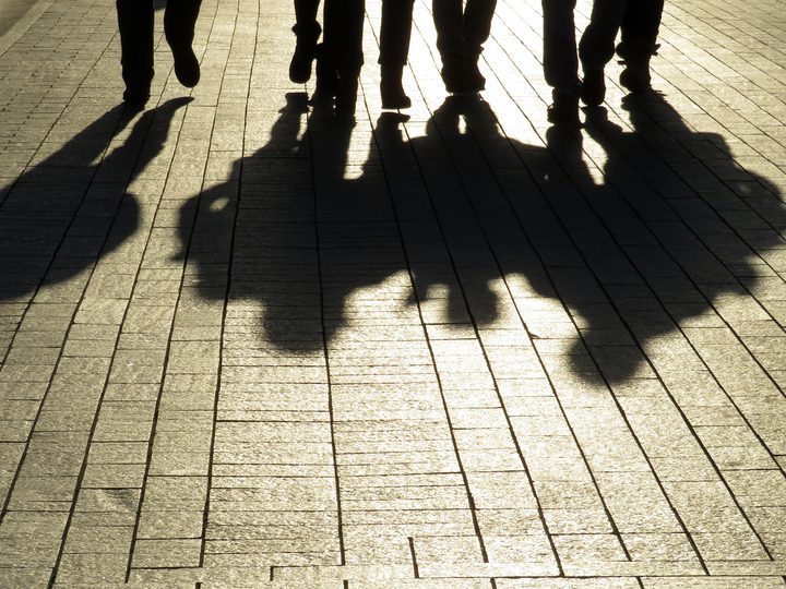 a group of people standing next to each other on a sidewalk