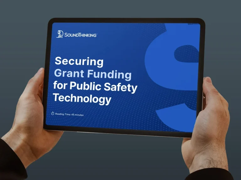 Two hands holding a tablet with the wording, Securing Grant Funding for Public Safety Technology in white lettering on a blue background.