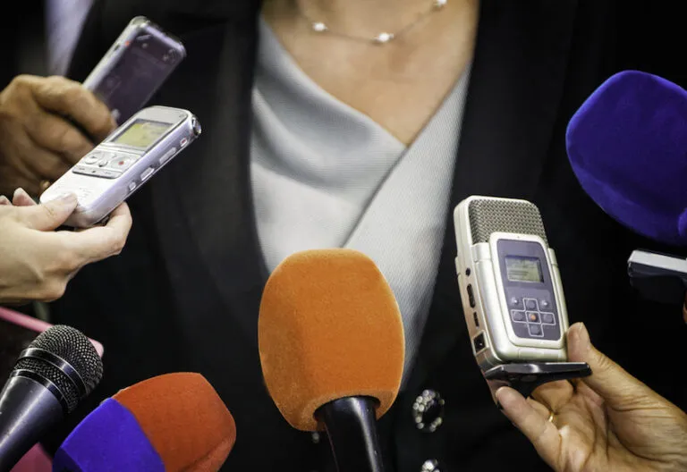 a group of people standing around microphones holding cell phones