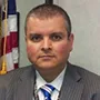 a man in a suit and tie in front of a flag