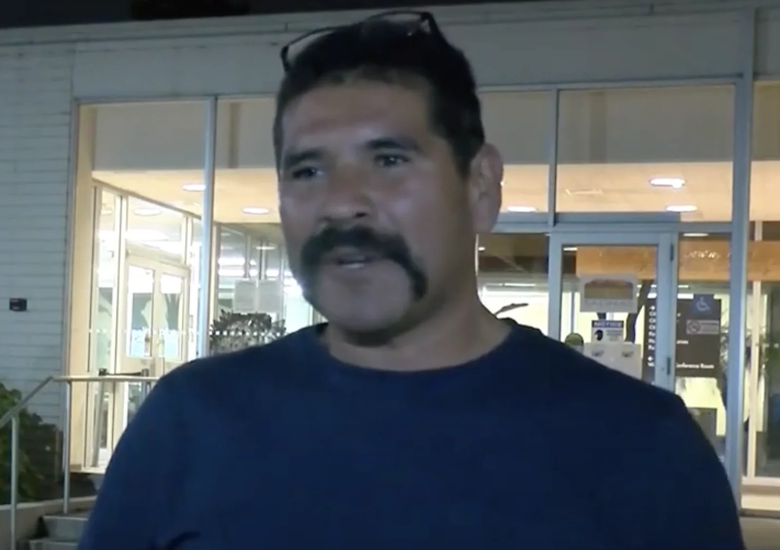 a man with a moustache standing in front of a building