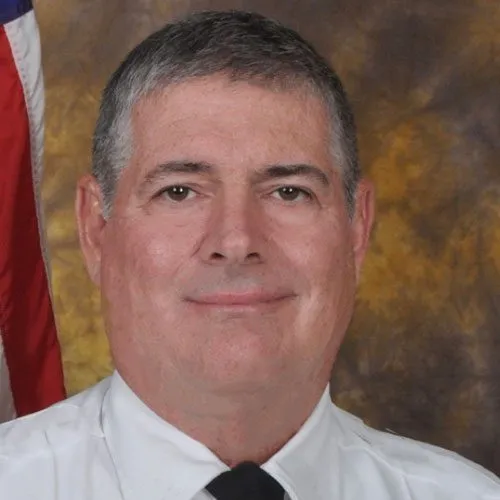 a man in a white shirt and tie in front of an american flag