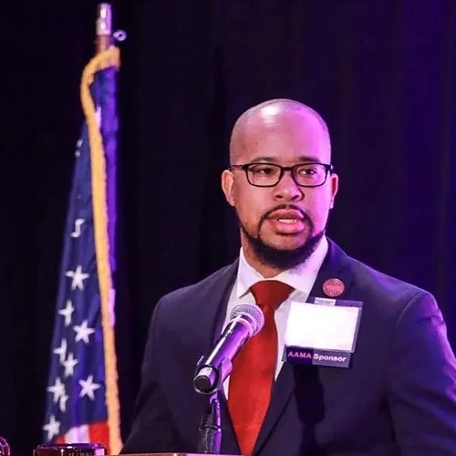 a man in a suit and tie speaking into a microphone