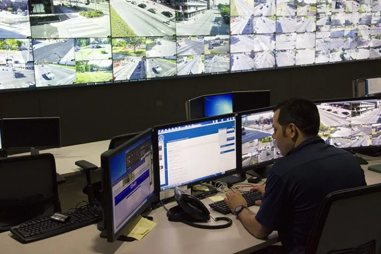 a man sitting at a desk in front of three monitors