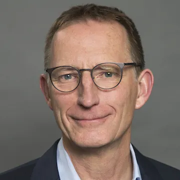 a man in a suit and glasses smiling at the camera