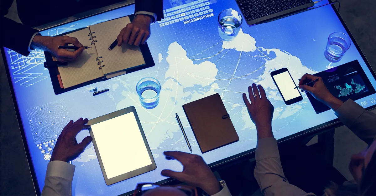 a group of people sitting around a table with electronic devices