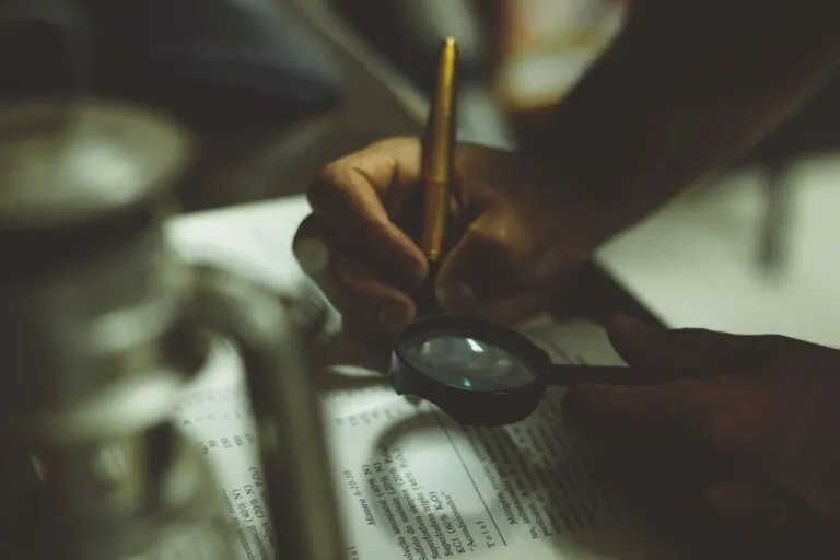 a person holding a magnifying glass over a piece of paper