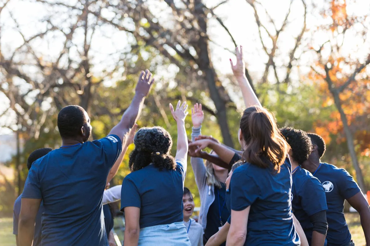 a group of people reaching up to catch a frisbee