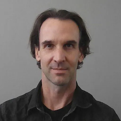 a man in a black shirt is looking at the camera