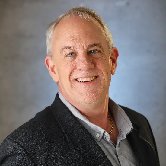 a man in a black jacket smiling at the camera