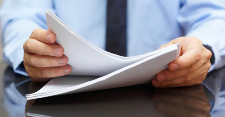 a man in a blue shirt and tie holding a piece of paper