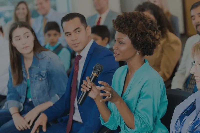 a woman holding a microphone in front of a group of people