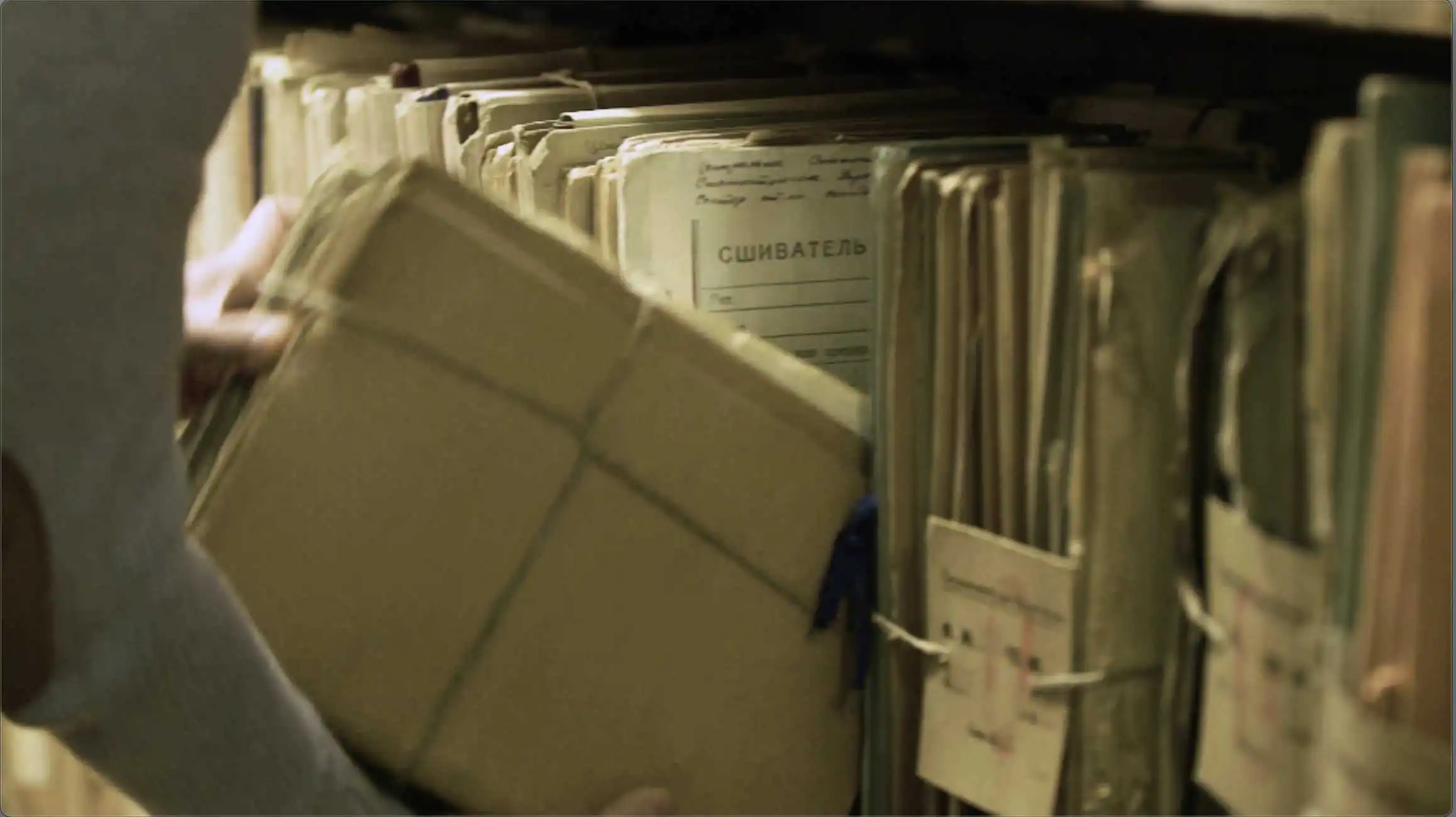 a person holding a box in front of a shelf full of files