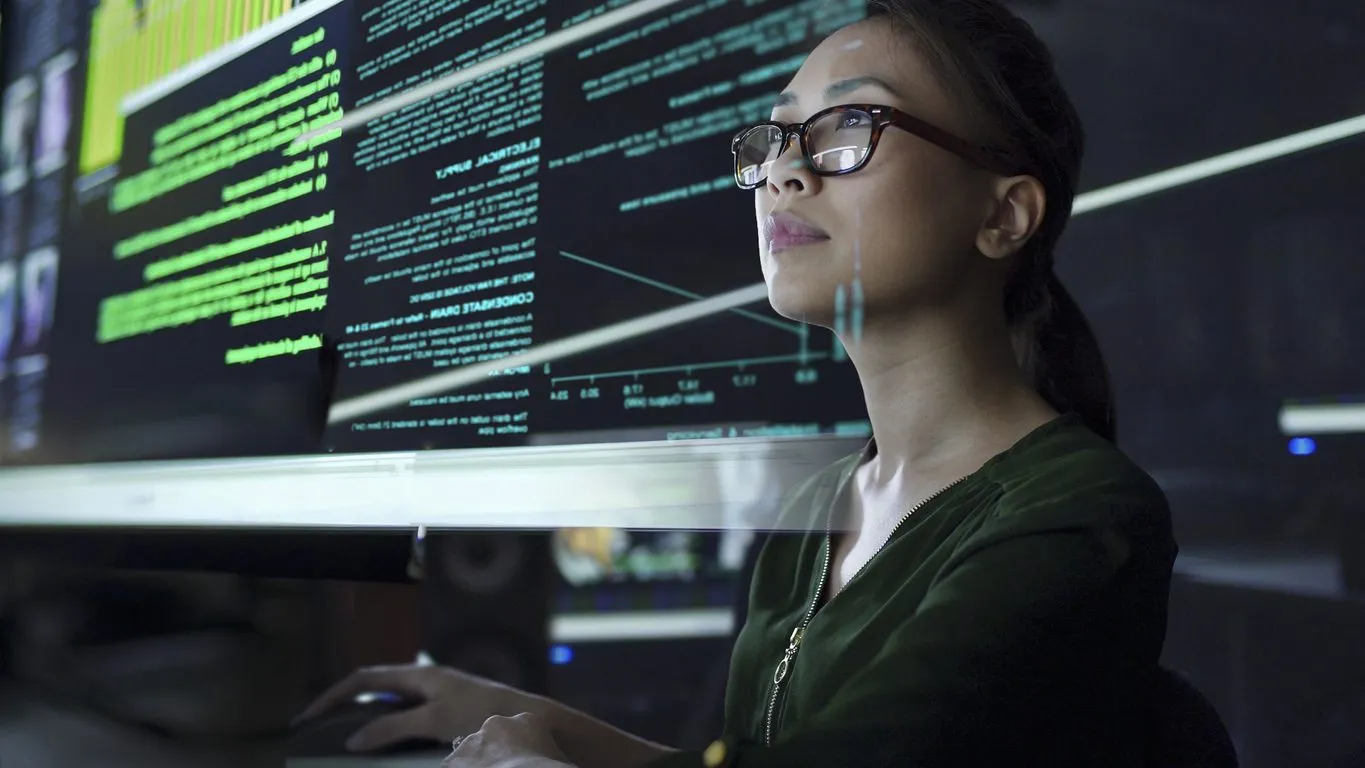 a woman wearing glasses is looking at a computer screen