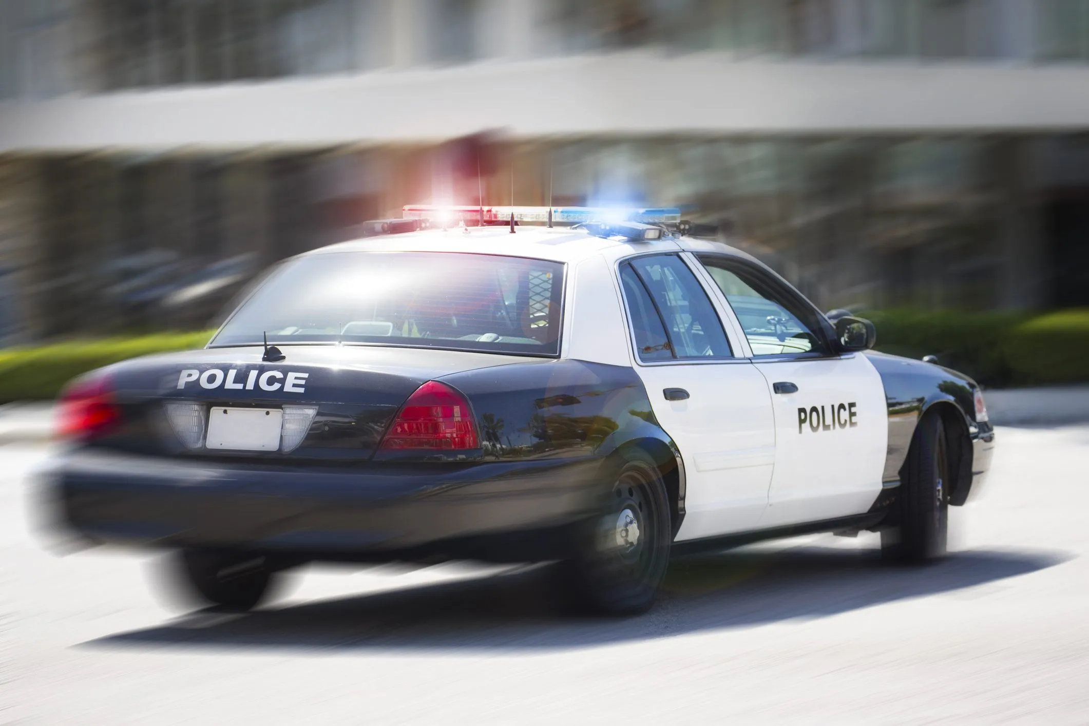 a police car driving down a street next to a tall building