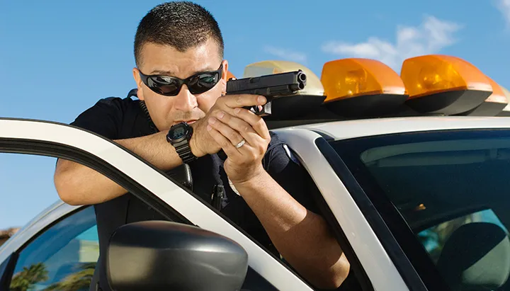 a man holding a gun while leaning on a car