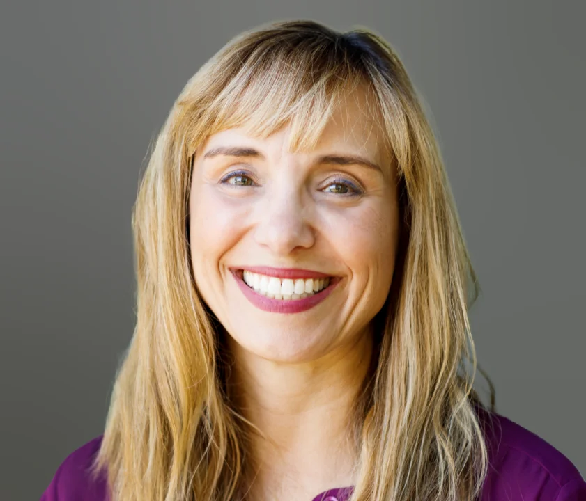 a woman with long blonde hair smiling at the camera