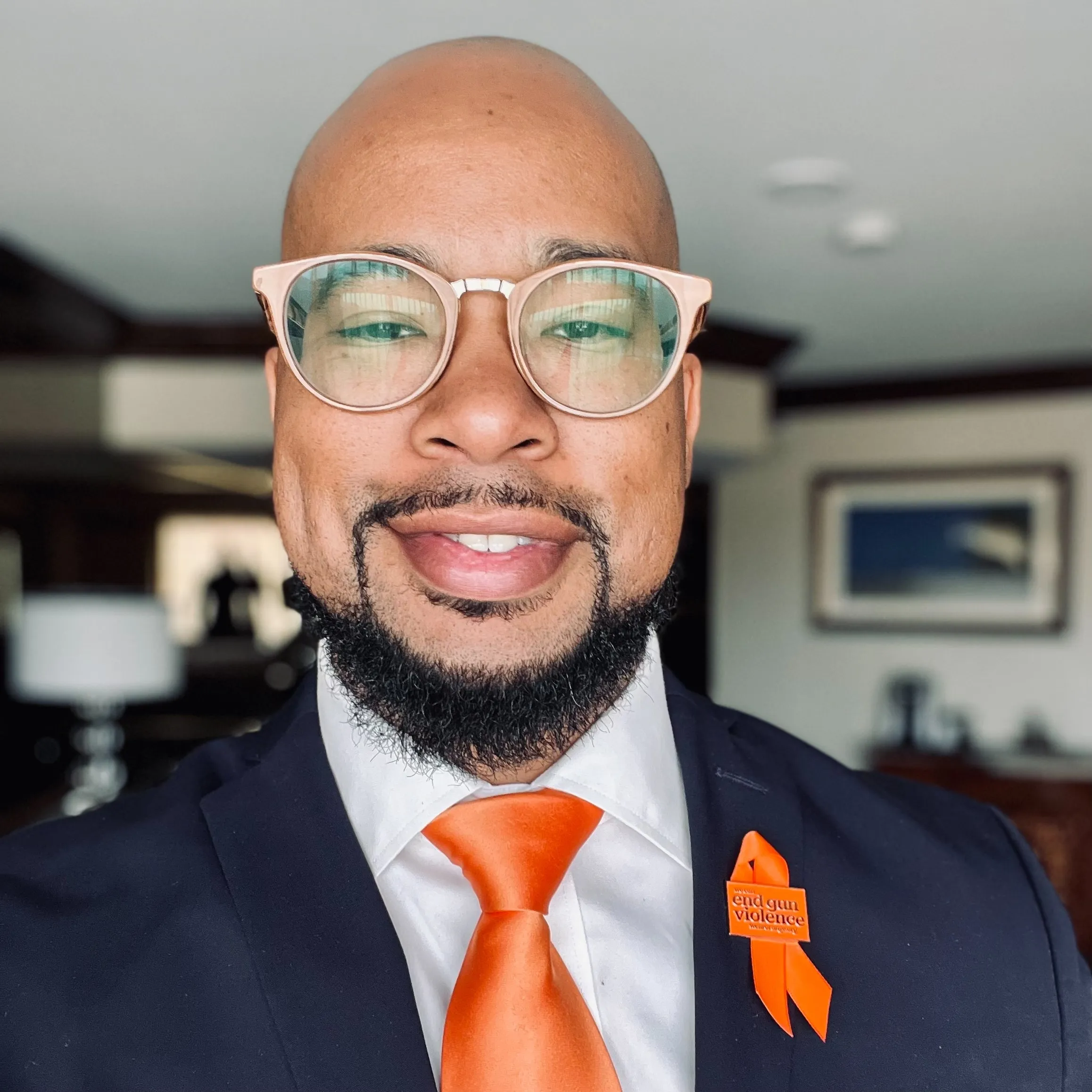 a man with a beard wearing a suit and orange tie