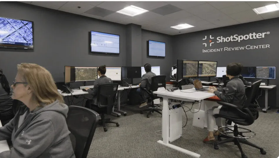 Image of ShotSpotter's Incident Review Center; a room with multiple computers, screens and operators.